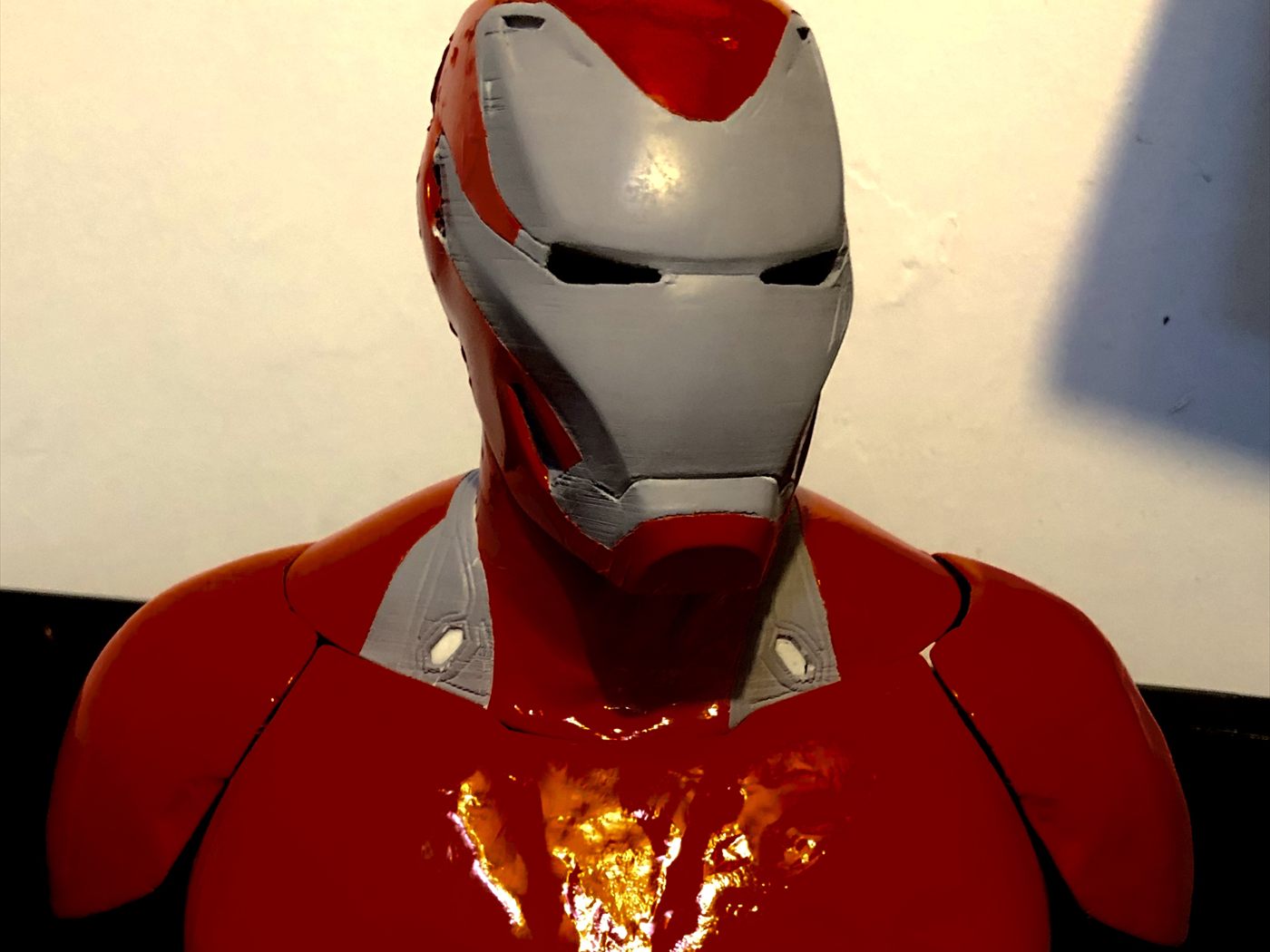 El busto pintado en rojo y plata, con el reactor del pecho iluminado.