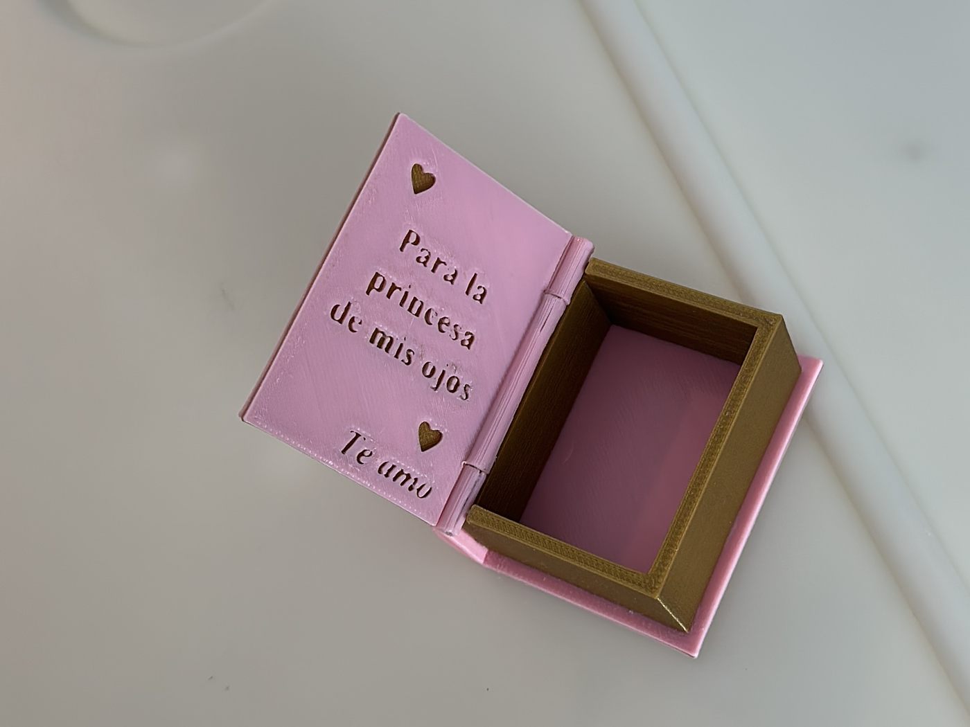 La caja abierta, con el compartimento forrado en dorado y una dedicatoria en relieve en la contratapa.