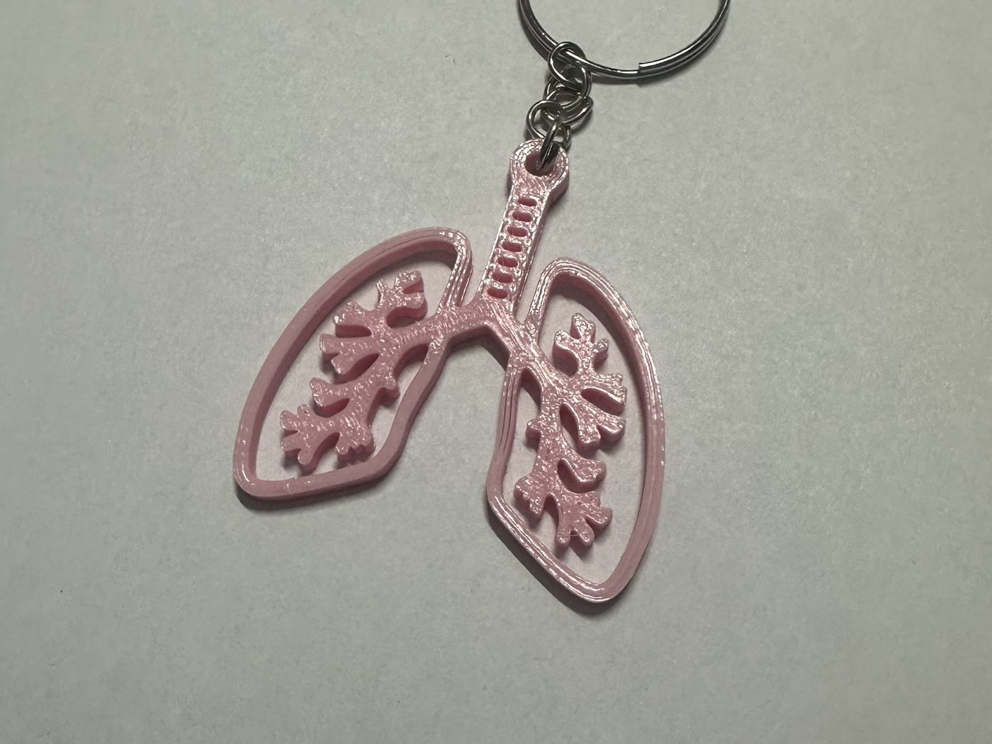Llavero con forma de pulmones impreso en 3D en rosa, con los bronquios calados.
