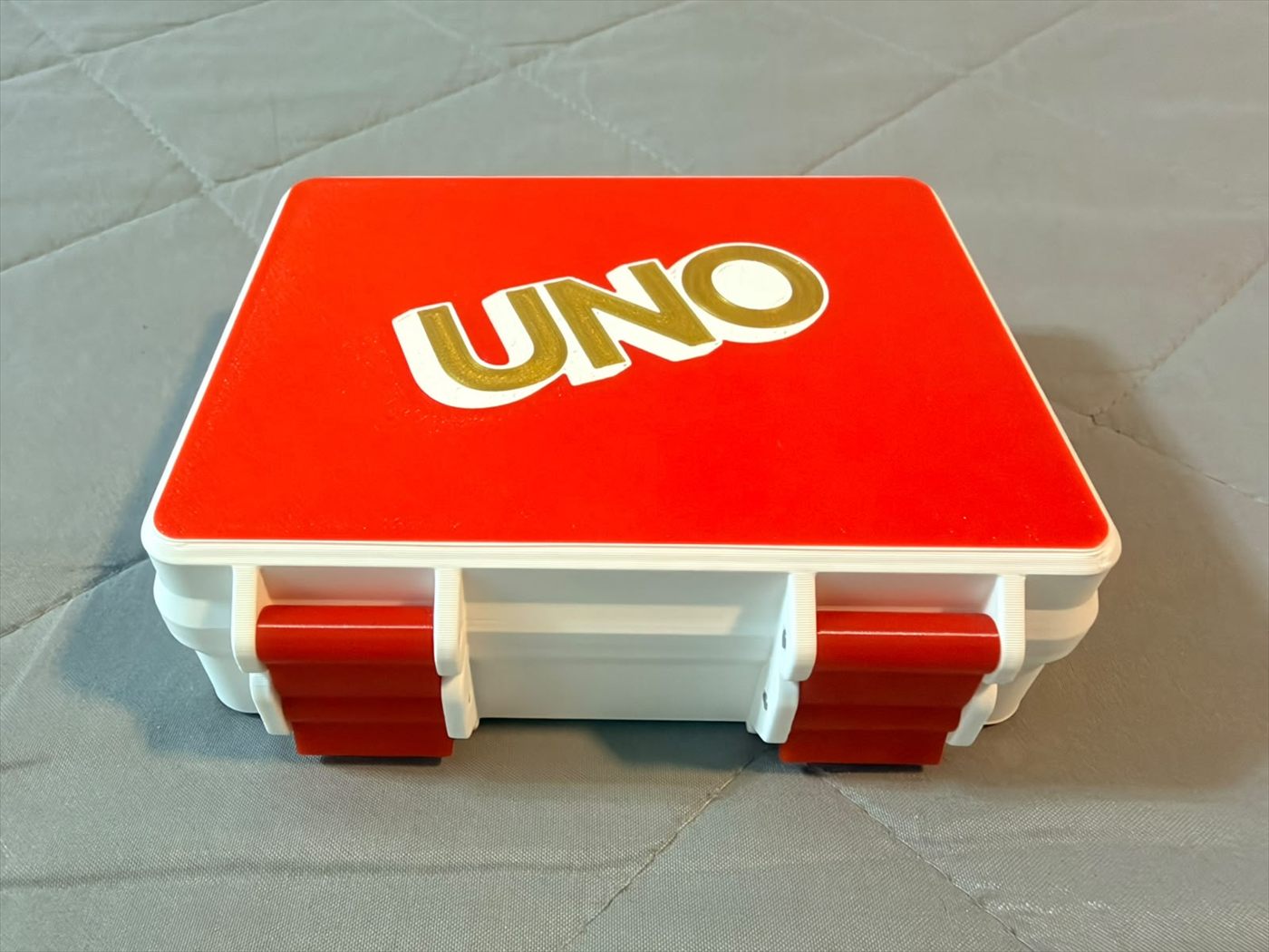 La caja impresa en blanco y rojo, con el logo de UNO en relieve sobre la tapa.