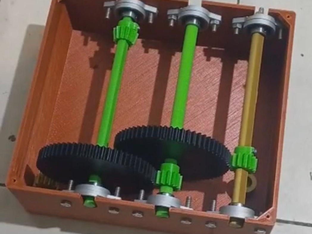 La caja de engranajes impresa en 3D, abierta, con tres ejes, engranajes y rodamientos a la vista.