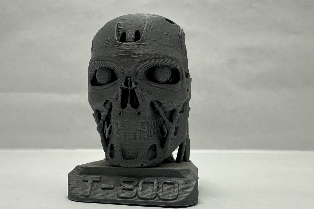 Busto del T-800 impreso en 3D en filamento gris, con su base rotulada.